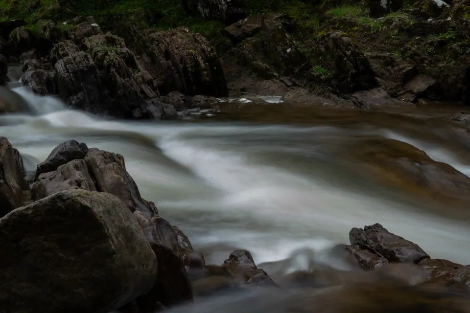 Long-exposure water forms a smooth white ribbon around large rocks