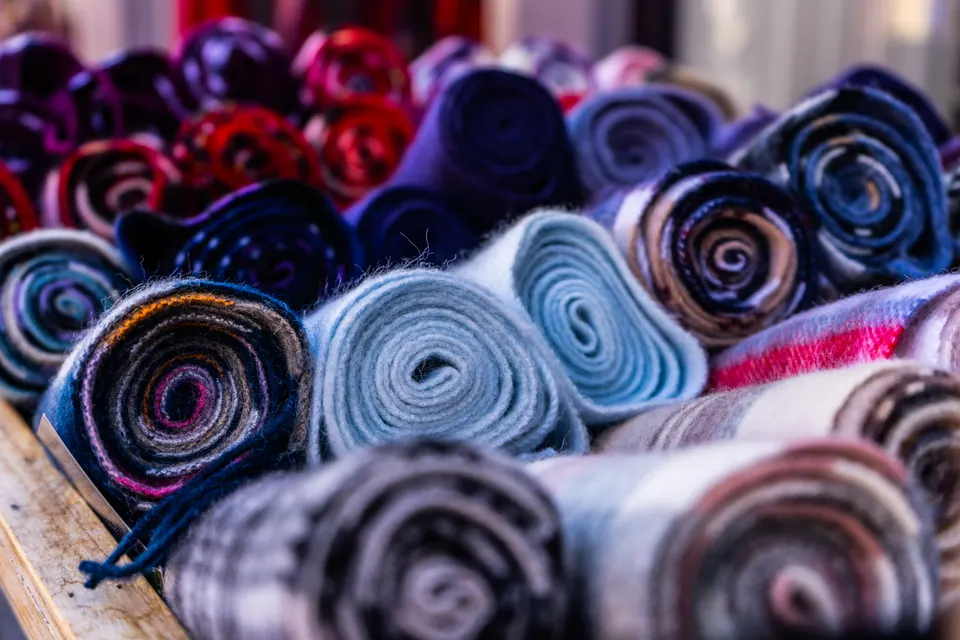 Rolls of patterned fabric packed together, their spirals in blue, grey, purple and red.