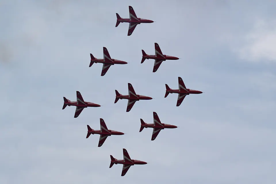 Nine red aircraft form a diamond seen directly from below