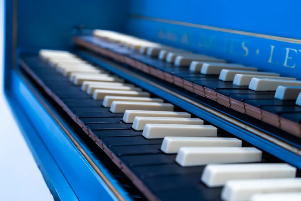 A close view along the black and white keys of a bright blue keyboard instrument.