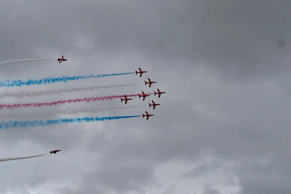 Aircraft peel away from parallel red, white and blue smoke trails
