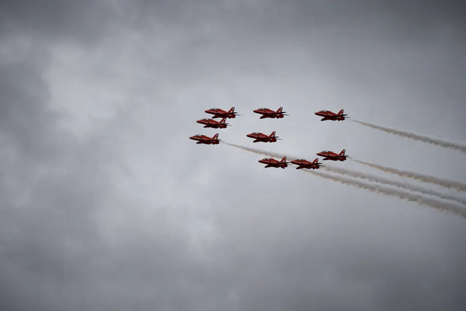 Aircraft fly in a close formation across a softly clouded grey sky